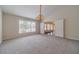 Bright living room with plush carpet, elegant chandelier, and large window with view of landscaped yard at 1022 Pecan Grove Pl, Lawrenceville, GA 30046