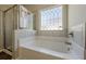 Bright bathroom featuring a bathtub, glass enclosed shower, and decorative privacy window at 207 Cherokee Reserve Cir, Canton, GA 30115