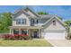 Charming two-story home featuring a covered porch and blooming roses in the front yard at 207 Cherokee Reserve Cir, Canton, GA 30115