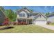 Charming two-story home featuring a well-manicured lawn and vibrant red flowers at 207 Cherokee Reserve Cir, Canton, GA 30115