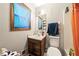 Cozy bathroom featuring a single sink vanity, toilet, mirror, and a shower with an orange curtain at 3955 Old Fairburn Sw Rd, Atlanta, GA 30331