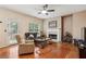 Cozy living room featuring hardwood floors, a fireplace, a ceiling fan, and natural light at 4560 Weathervane Dr, Alpharetta, GA 30022