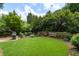 Private backyard oasis featuring a lush green lawn, stone patio and mature landscaping at 400 Fieldstone Lndg, Alpharetta, GA 30005