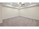 A carpeted empty bedroom featuring a tray ceiling and natural light at 6615 Callanwalde Ct, Suwanee, GA 30024