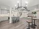 Open-concept living room with a modern chandelier, kitchen island with bar stools, and a cozy fireplace at 6615 Callanwalde Ct, Suwanee, GA 30024