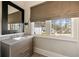 Chic powder room with modern vanity, sleek mirror, and window offering a view of the outdoors, adding charm and functionality at 810 Kenry Ct, Atlanta, GA 30342