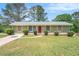 Charming one-story home with a well-manicured lawn, shutters and a welcoming red front door at 898 Doeskin Nw Dr, Conyers, GA 30012