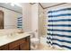 Bathroom featuring a single vanity, toilet, and bathtub with a blue and white striped shower curtain at 929 Hampton Nw Trl, Lilburn, GA 30047