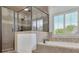 Bright bathroom showcasing a glass-enclosed shower, soaking tub, and shuttered window at 2932 Springbluff Ln, Buford, GA 30519