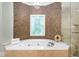 A modern corner soaking tub surrounded by decorative tile work and next to a glass enclosed shower at 8345 Jett Ferry Rd, Sandy Springs, GA 30350