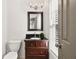 Bathroom vanity with dark wood cabinet, black countertop, framed mirror, and modern light fixture at 3362 Alexis Ct, Marietta, GA 30066