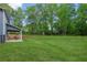 Expansive backyard with lush green grass and a covered patio area, surrounded by mature trees at 7031 Palomino Trl, Winston, GA 30187