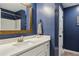 Stylish bathroom with a wood-framed mirror, white vanity, and sleek fixtures, enhanced by a blue accent wall at 7031 Palomino Trl, Winston, GA 30187