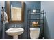 Elegant half bathroom with a white pedestal sink, rustic mirror, and a shelving unit for storage at 7031 Palomino Trl, Winston, GA 30187
