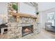 Living room stone fireplace with wooden mantle and mirror above, next to sunlit sitting area at 4185 Cami Way, Buford, GA 30519