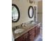 Bathroom featuring a double sink vanity, granite countertop, wood cabinets and decorative mirrors at 2435 Jakin Way, Suwanee, GA 30024