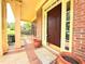 Close-up of a charming front porch with brick flooring, decorative columns, and a dark wood front door at 3500 Millwater Xing, Dacula, GA 30019