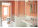 Elegant bathroom with white tile, pedestal sink, and decorative frosted glass window with peach walls at 4705 Paran Nw Vly, Atlanta, GA 30327