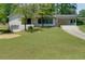 Charming white brick home with a well-maintained lawn and a long driveway leading to a carport at 1987 Darrell Dr, Marietta, GA 30066