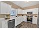 Open concept kitchen featuring white cabinets, stainless steel appliances, and wood-look flooring at 261 Venture Path, Hiram, GA 30141