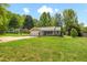 Charming single-story home with well-manicured lawn and inviting curb appeal surrounded by mature trees at 2035 Mountain Rd, Cumming, GA 30040