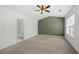 Carpeted bedroom featuring olive-colored accent wall, ceiling fan and ensuite bathroom offers a functional and comfortable layout at 5589 Trace Views Dr, Norcross, GA 30071