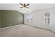 The bedroom features an olive-colored accent wall, ceiling fan, carpet and plenty of natural light from the large window at 5589 Trace Views Dr, Norcross, GA 30071