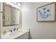 Stylish half bath features a white vanity with stone countertop, framed mirror, and decorative art at 6000 Hampton Bluff Way, Roswell, GA 30075