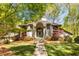 Stunning home exterior with an arched entryway, stone path, lush lawn, and colorful landscaping surrounded by mature trees at 6525 Old Riverside Nw Dr, Sandy Springs, GA 30328