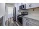 Modern kitchen featuring stainless steel appliances, white cabinets and grey wood floors at 223 Tuxworth Cir, Decatur, GA 30033