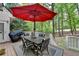 Outdoor deck with a table, chairs, and a large red umbrella for shade at 2973 Misty Rock Cv, Dacula, GA 30019
