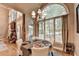 Sun-drenched dining area with a large arched window, chandelier, and views of the wooded backyard at 2973 Misty Rock Cv, Dacula, GA 30019