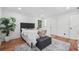 Cozy bedroom showcasing a tufted headboard, hardwood floors, and lots of natural light at 4327 Wellington Hills Ln, Snellville, GA 30039
