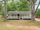 Charming single-story home with a welcoming front porch, framed by mature trees at 5438 Hiram Lithia Springs Rd, Powder Springs, GA 30127
