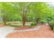 Scenic backyard featuring a putting green, mature trees, brick pathway, and lush landscaping at 9465 Grande Dr, Winston, GA 30187