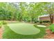 Private putting green featuring manicured synthetic grass, a sand trap, and mature landscaping at 9465 Grande Dr, Winston, GA 30187