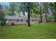 View of the backyard featuring green grass, mature trees, and brick house at 2732 Elkhorn Dr, Decatur, GA 30034