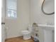 Cozy half bathroom featuring a pedestal sink, modern toilet, and natural light from the window at 571 Hancock Se Dr, Atlanta, GA 30354