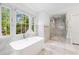 Bright bathroom featuring a soaking tub, a glass-enclosed shower, and large windows with views of the outdoors at 893 E Rock Springs Ne Rd, Atlanta, GA 30306