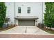 Exterior shot of a two-car garage showing curb appeal with green grass and a tree on the right side at 130 Forrest Aly, Roswell, GA 30075