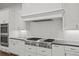This kitchen features an ample gas range, white cabinetry, subway tile backsplash, and modern appliances at 130 Forrest Aly, Roswell, GA 30075