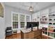 Bright home office featuring built-in bookshelves and a large desk illuminated by natural light from a large window at 5155 Amberden Hall Dr, Suwanee, GA 30024