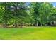 Lush backyard with mature trees and a serene pond, offering a tranquil escape at 7180 Westray Rd, Cumming, GA 30028