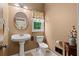 Charming bathroom featuring a pedestal sink, toilet, and window at 7180 Westray Rd, Cumming, GA 30028