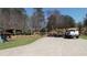 Wide driveway leads to a home featuring a large yard, landscaping, and parked vehicles at 7180 Westray Rd, Cumming, GA 30028