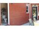 Exterior view of red brick home with outdoor seating area and half bath at 7180 Westray Rd, Cumming, GA 30028