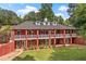 Sprawling brick home featuring a double porch, manicured lawn, and mature trees for an inviting curb appeal at 7180 Westray Rd, Cumming, GA 30028