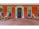 Charming front entrance featuring a dark-colored door, classic brickwork, and comfortable rocking chairs at 7180 Westray Rd, Cumming, GA 30028