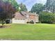 Beautiful home with a well-manicured lawn, mature trees, and a charming front exterior featuring brick and siding at 130 Floss Flower Ct, Roswell, GA 30076