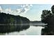 A serene lake with calm waters, lush green trees, and a tranquil atmosphere at sunrise or sunset at 130 Floss Flower Ct, Roswell, GA 30076